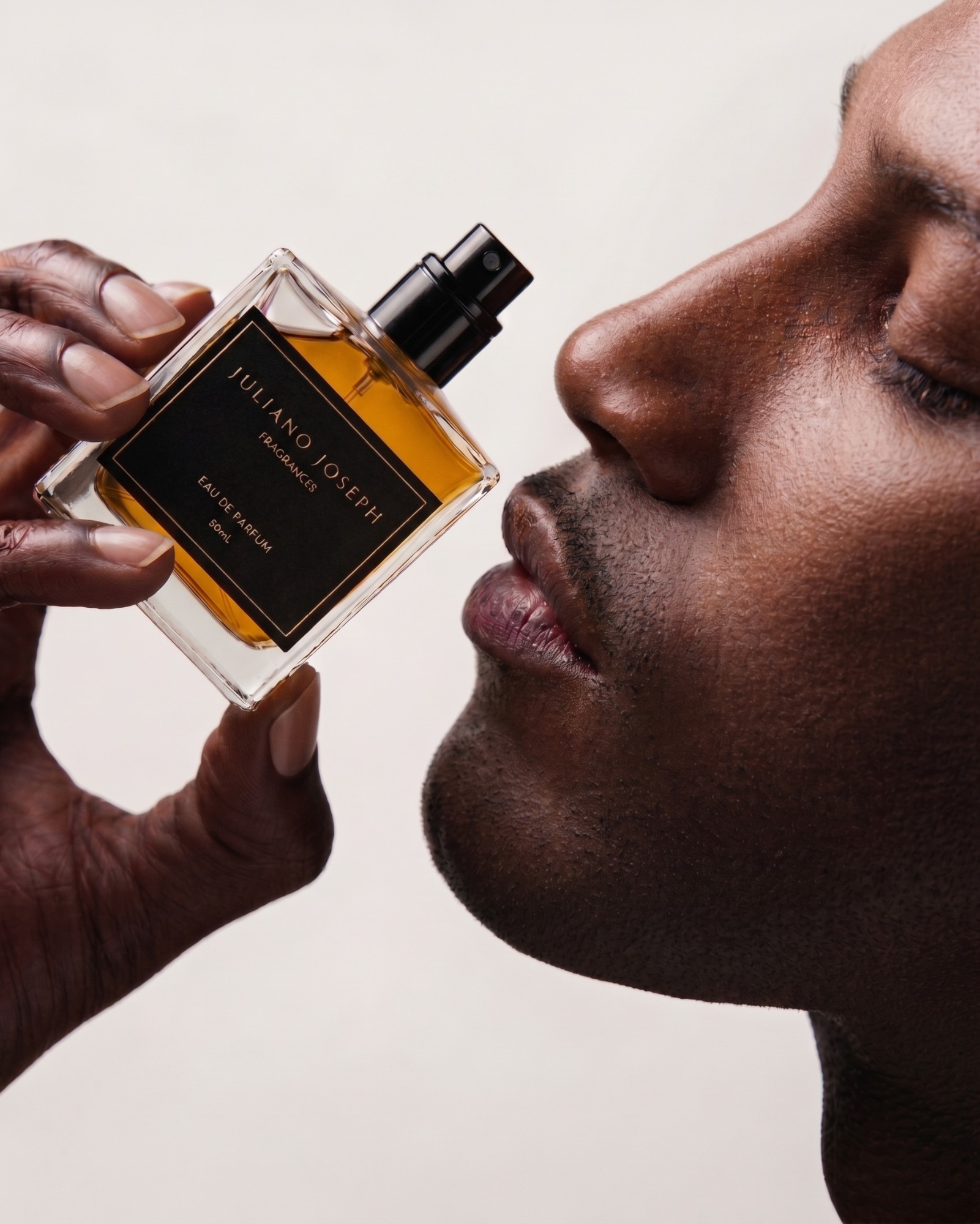 Man closing his eyes while smelling a Juliano Joseph bottle
